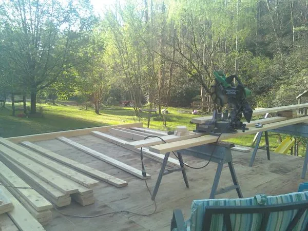 Miter saw and framing lumber on a deck under construction in Windsor